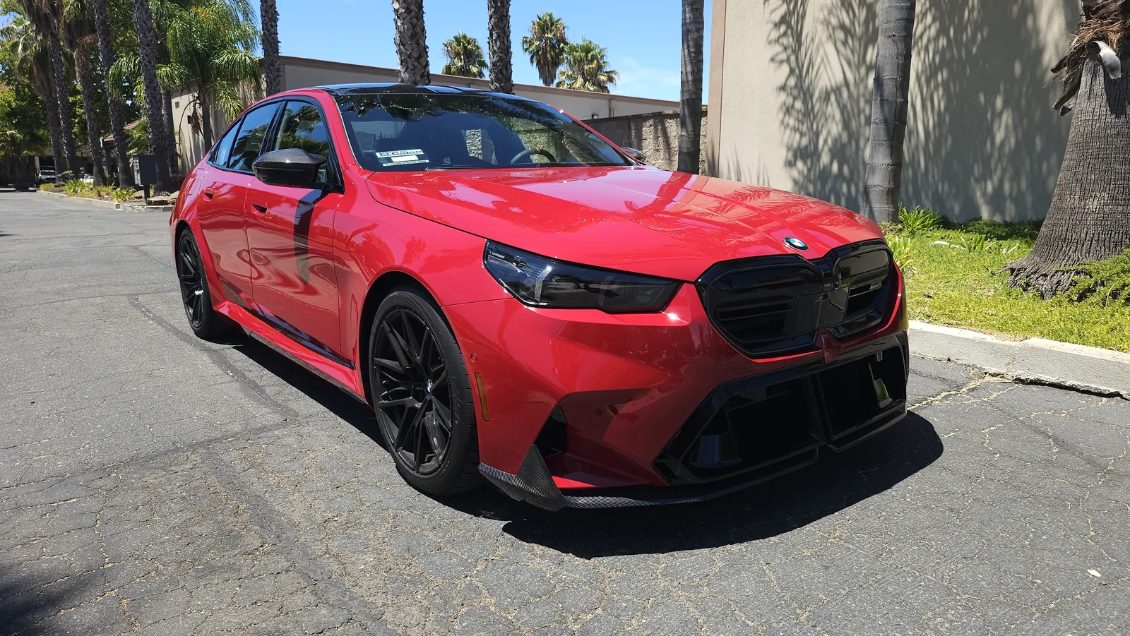 Red BMW M5 with tinted windows outside the shop