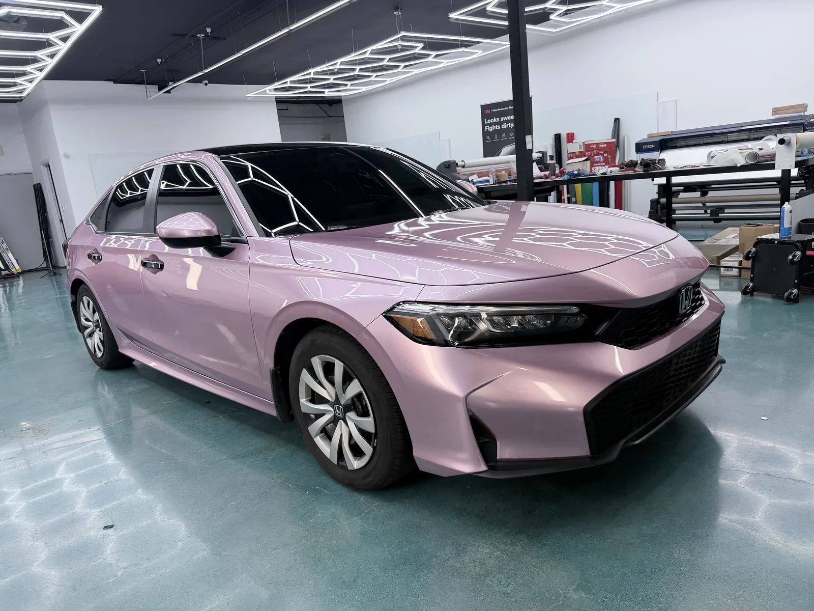 Honda Civic in a pink pearl wrap inside the shop